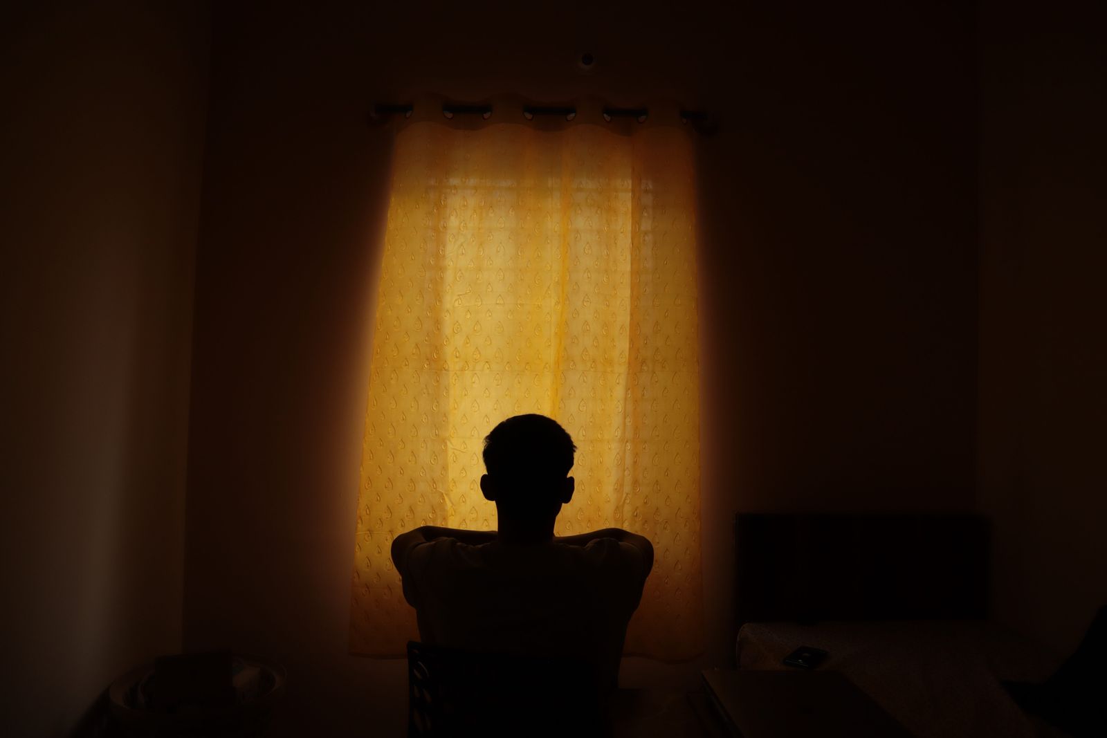 Silueta unui copil singur pe întuneric, lumină difuză de la fereastră - copilul interior care se ascunde și așteaptă să fie văzut