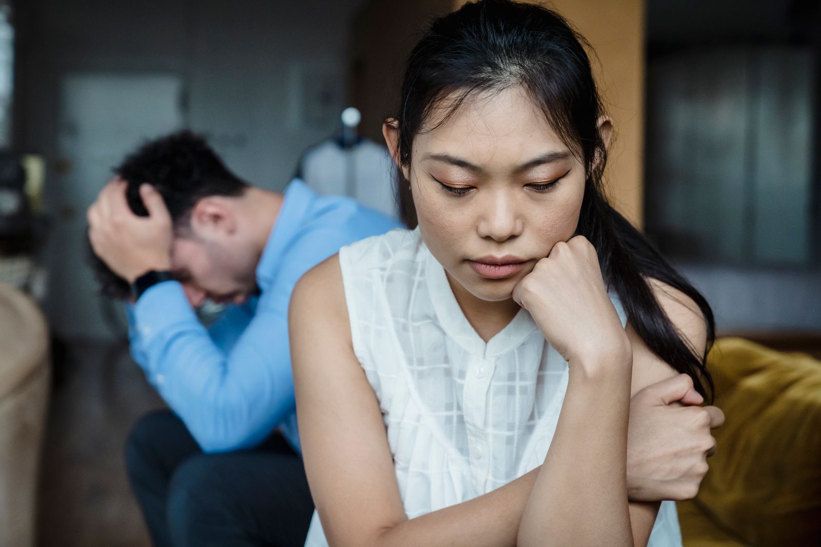 Parteneri stând pe aceeași canapea, fiecare retras în propria lume, simțind disconfortul emoțional al îndepărtării
